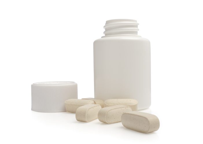Open pill jar with scattered pills